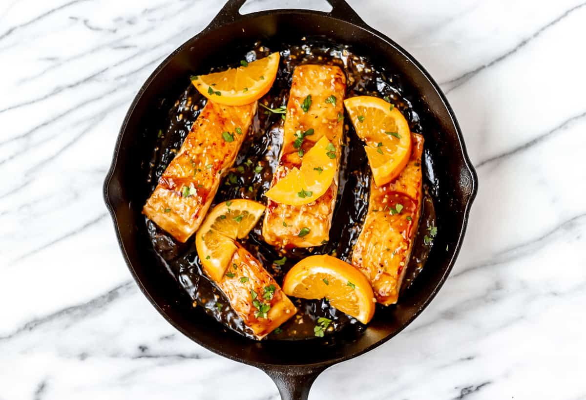 Orange glazed salmon in a cast iron pan.