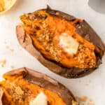 Overhead of two air fryer sweet potatoes with butter and brown sugar on them.