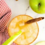 Apple cider margarita in a glass with cinnamon sticks and an apple slice with text overlay.