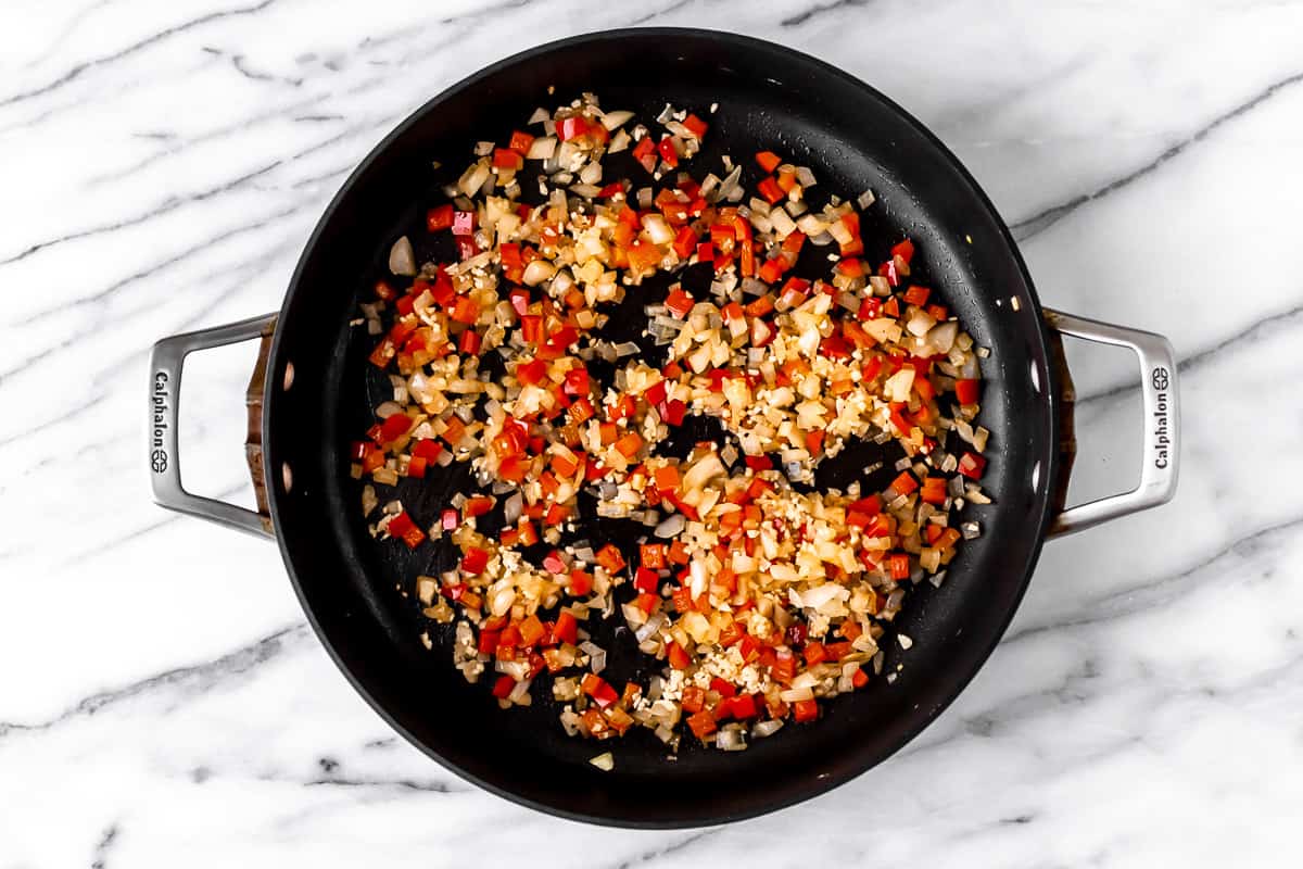 Onion, pepper and garlic cooking in a black skillet.