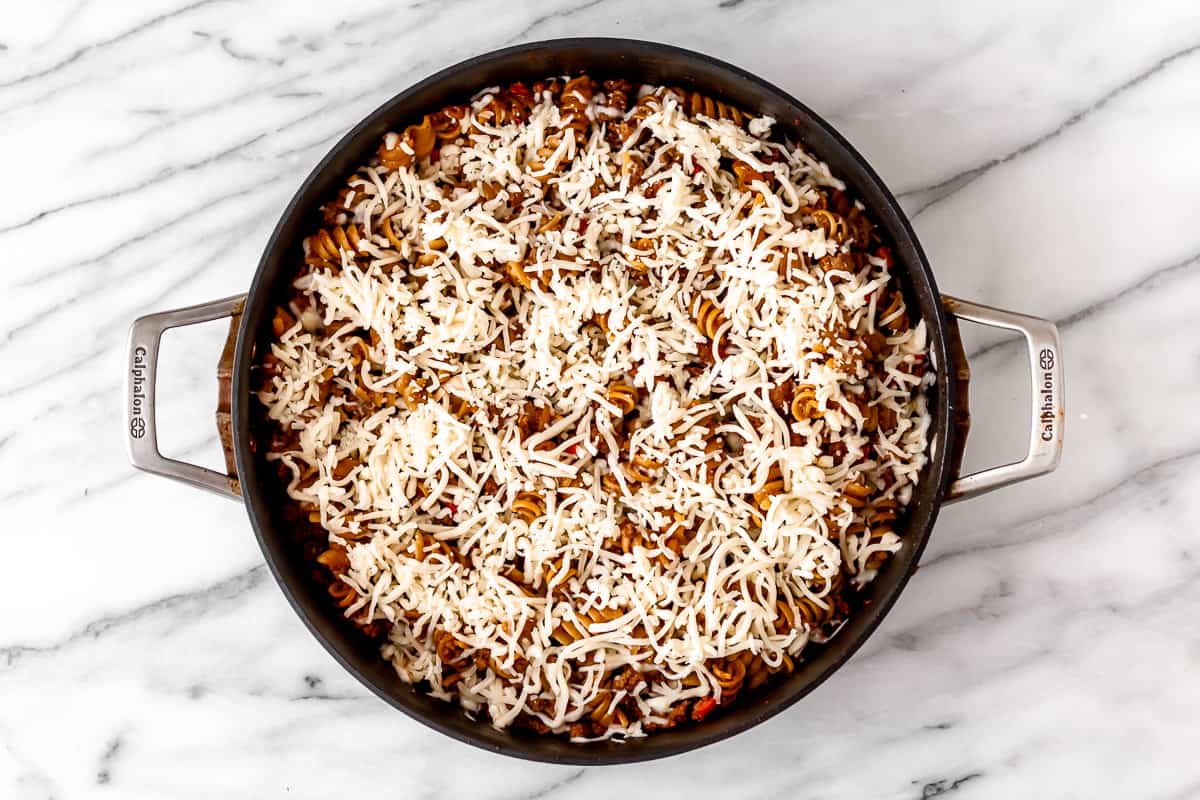 Ground beef pasta skillet topped with mozzarella cheese in a black skillet.