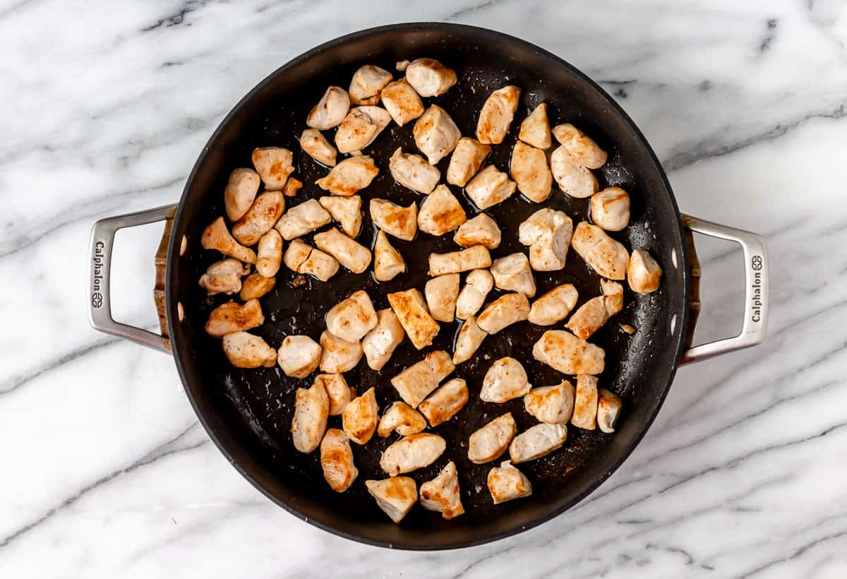 Diced chicken cooking in a skillet.