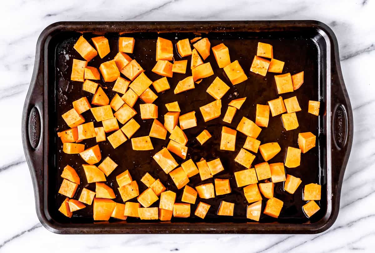 Raw sweet potato cubes on a baking sheet.