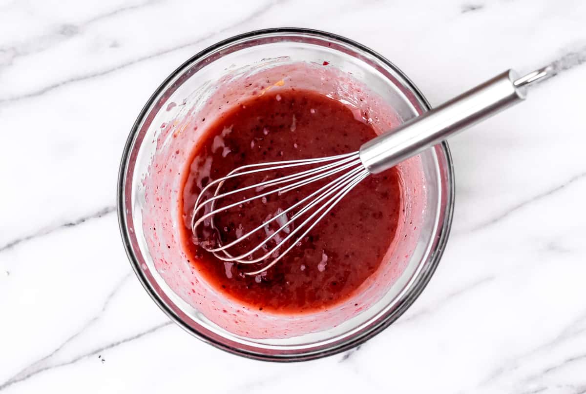 Cranberry salad dressing in a bowl with a whisk.