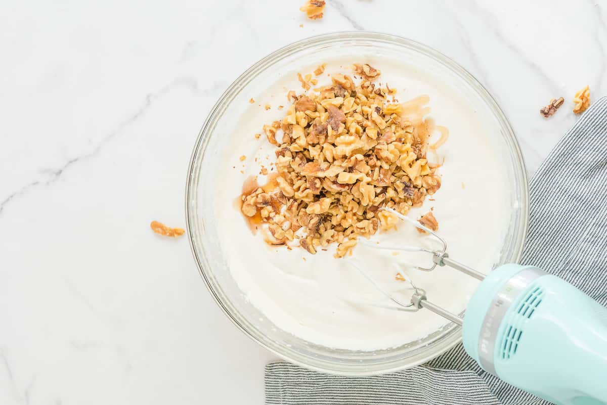 Ice cream mixture in a mixing bowl with walnuts on top.