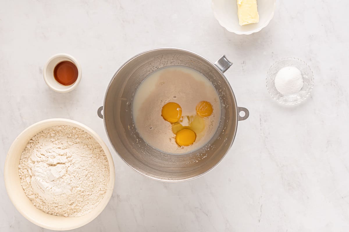 Eggs and yeast in a mixing bowl with other ingredients around it.