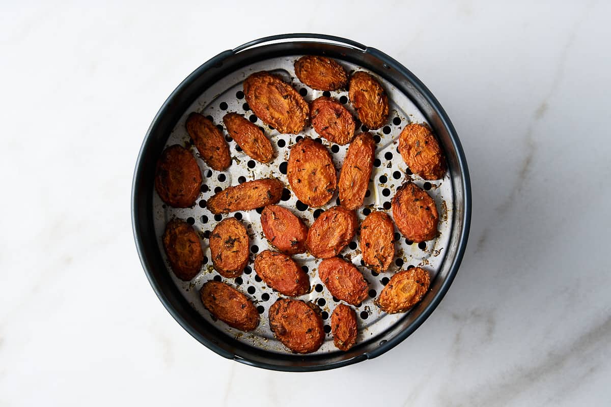 Seasoned air fried carrots in an air fryer basket.