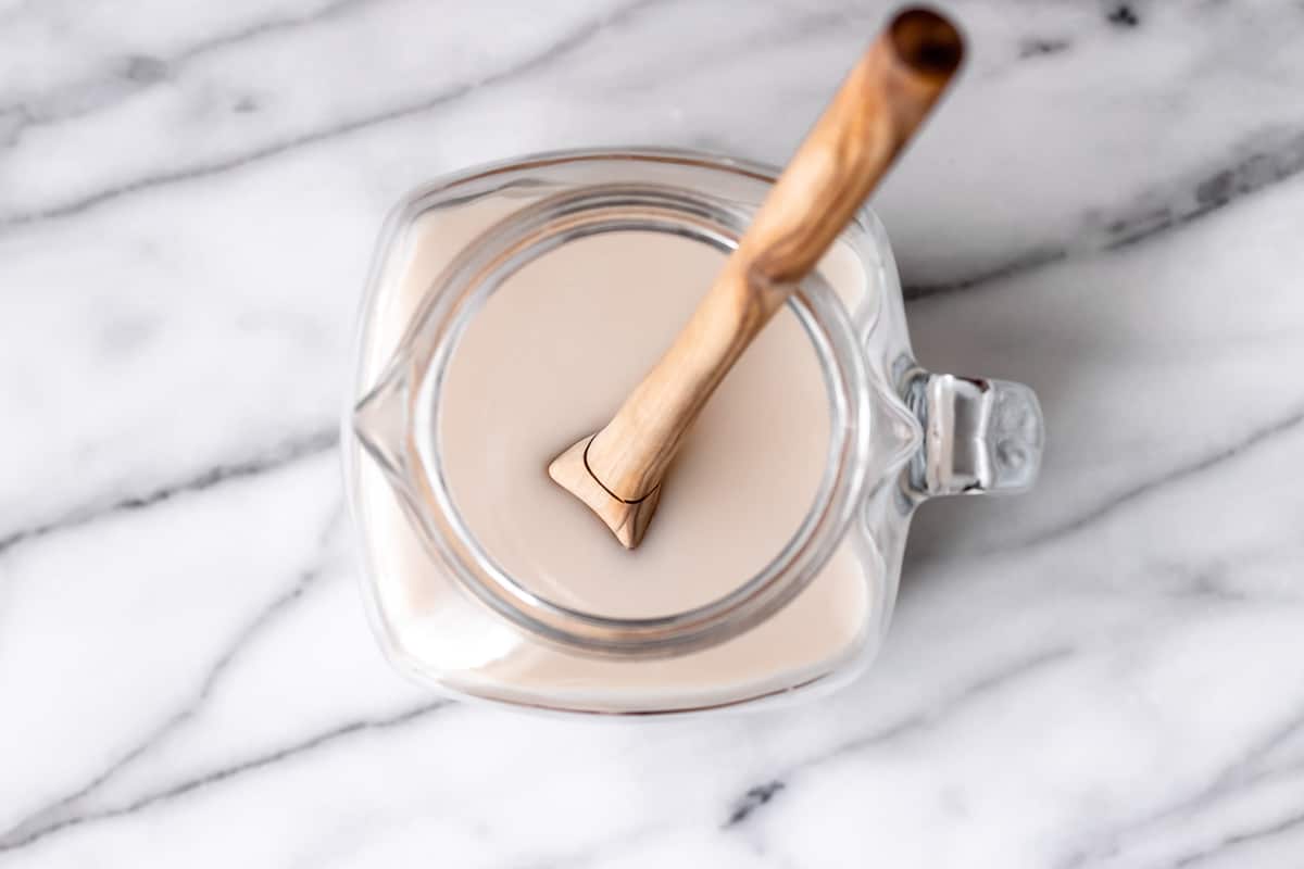 Overhead of horchata in a pitcher with a wood spoon in it.