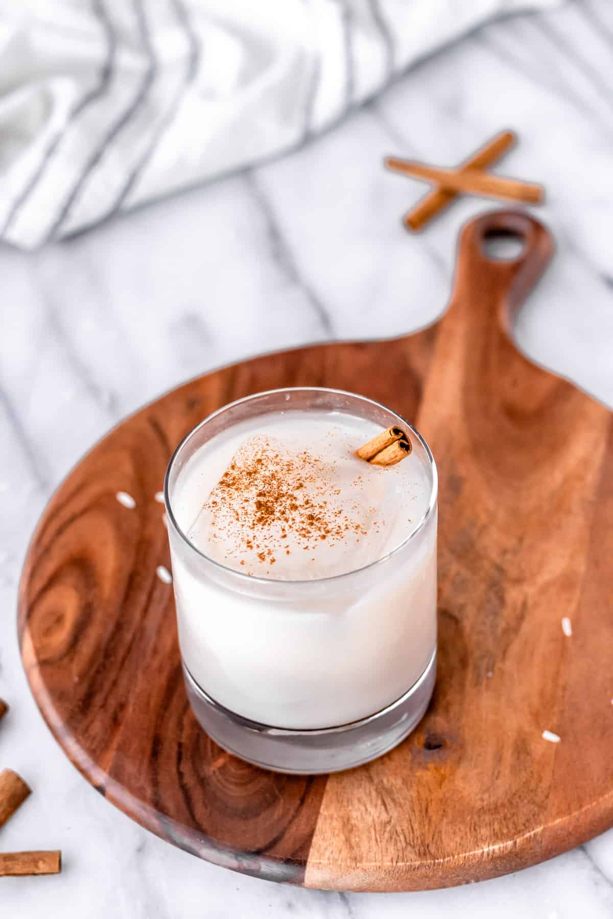 Ice coffee in glass mug with milk and cinnamon on wooden table in