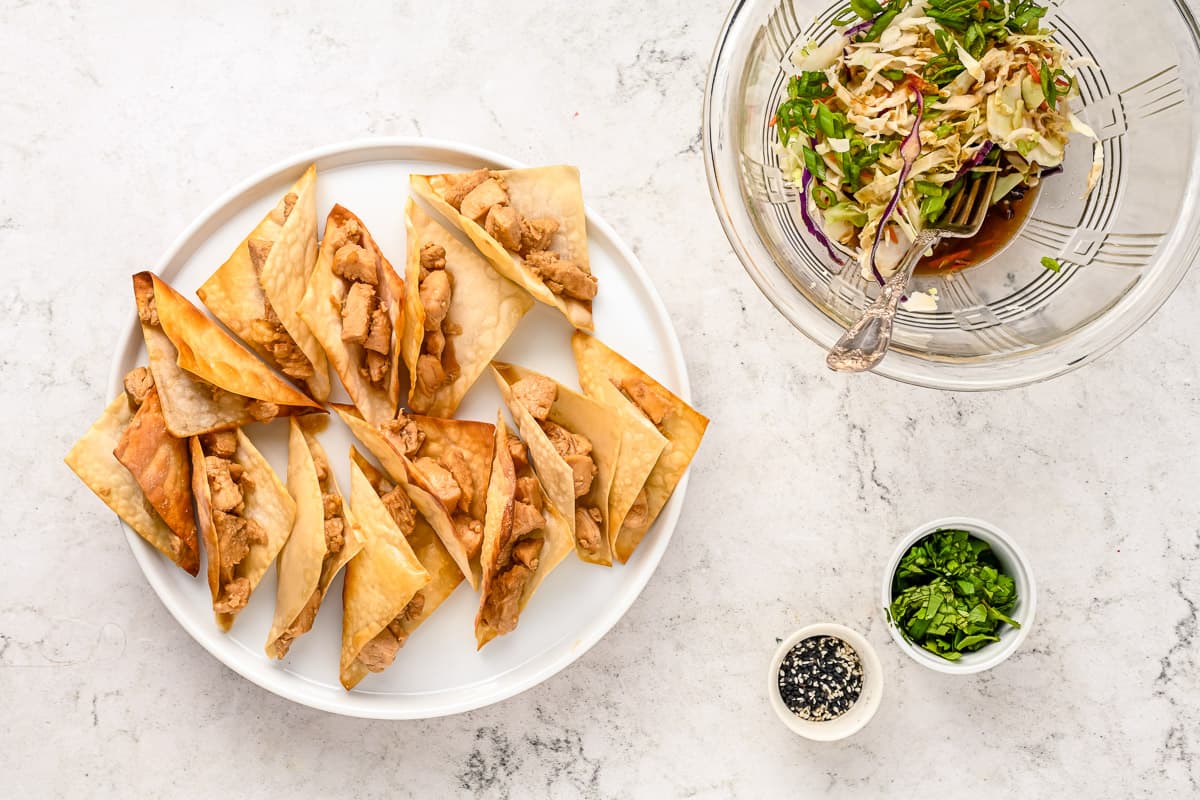 Wonton shells filled with chicken and cabbage slaw in a bowl off to the side.