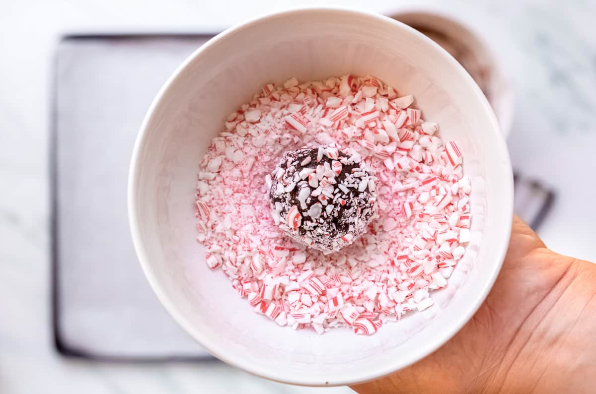 Chocolate dough ball in a bowl of crushed candy canes.