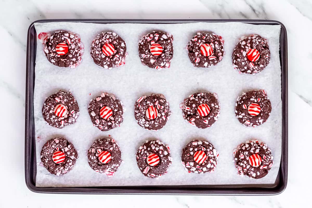 Baked chocolate peppermint cookies with a candy kiss in the center on a baking sheet.