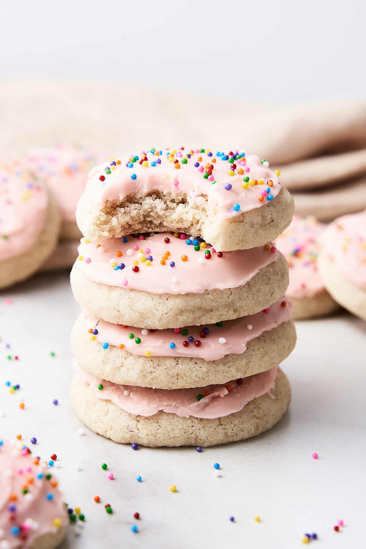 A stack of gluten free sugar cookies with a bite taken out of the top cookie.