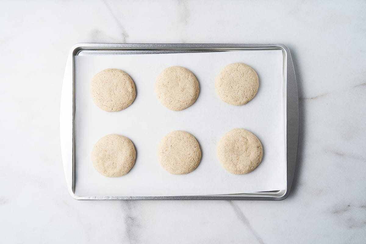 Six baked gluten free cookies on a sheet pan.