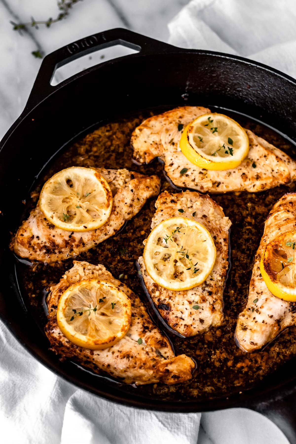 Five Greek Lemon Chicken breasts in a cast iron skillet.