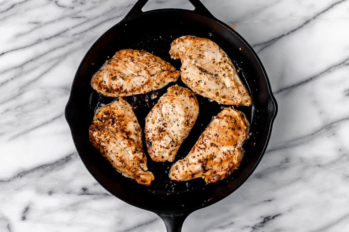 Browned chicken breasts in a cast iron skillet.