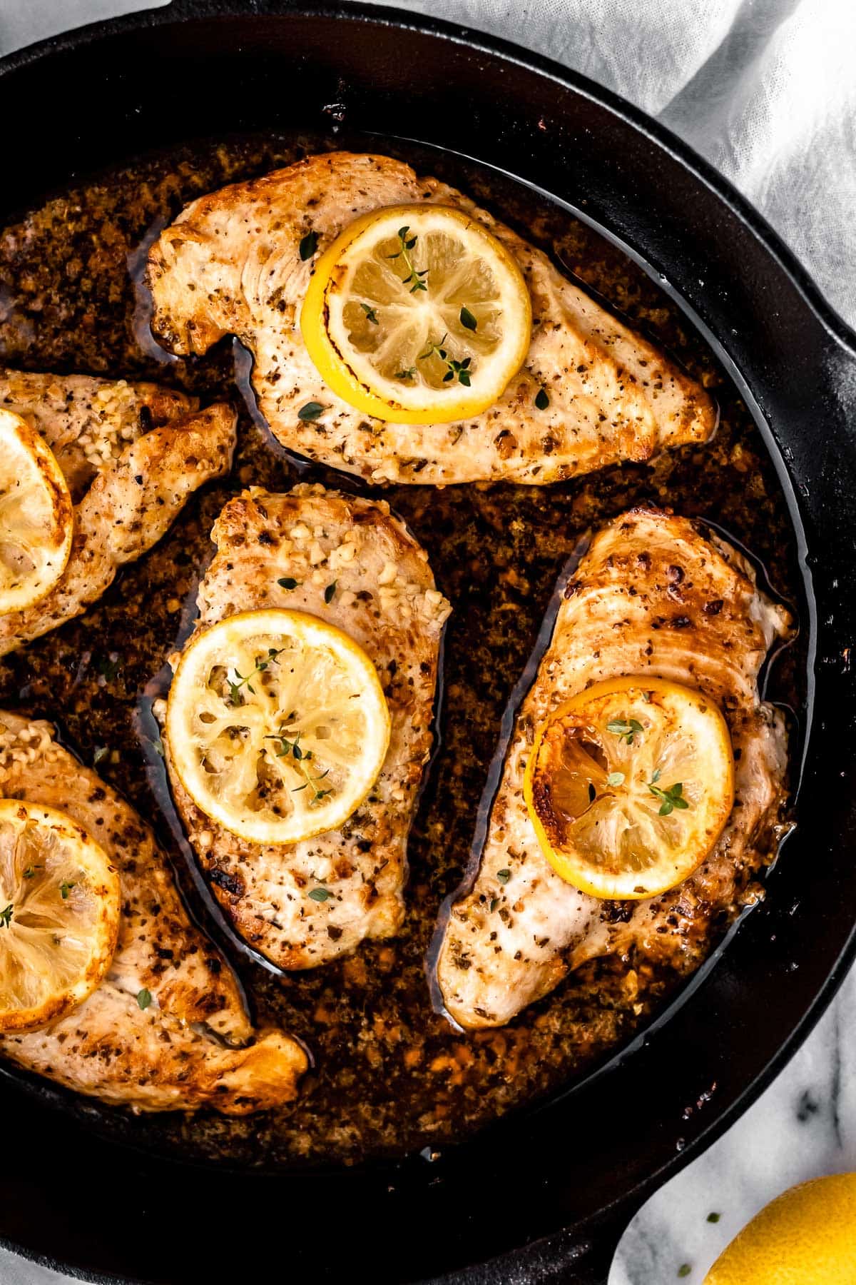 Overhead close up of Greek Style Braised Chicken in a cast iron skillet.