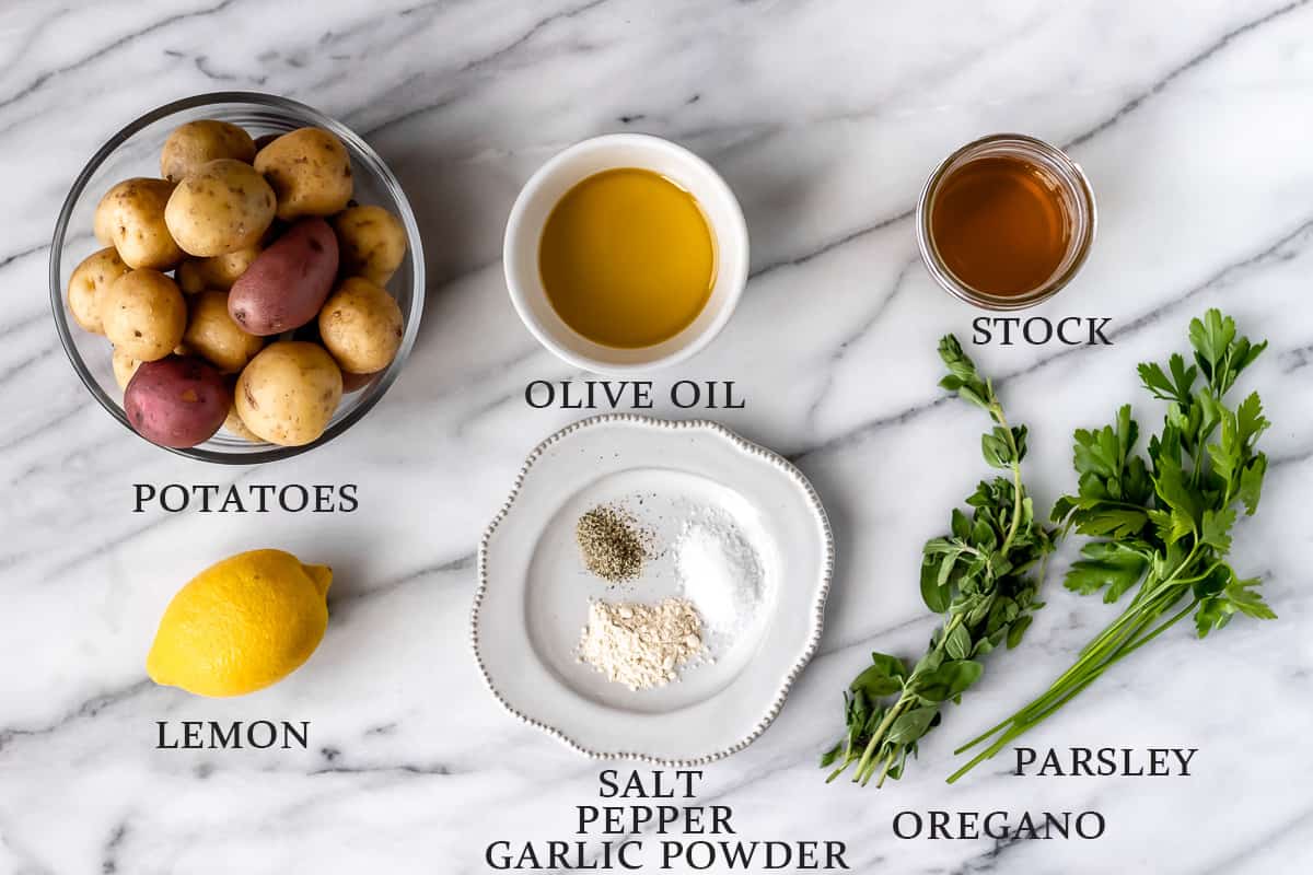 Ingredients for Greek roasted potatoes on a marble background with text overlay.