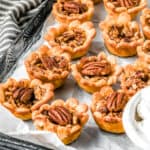 Mini Pecan Pies on a parchment paper lined baking sheet.