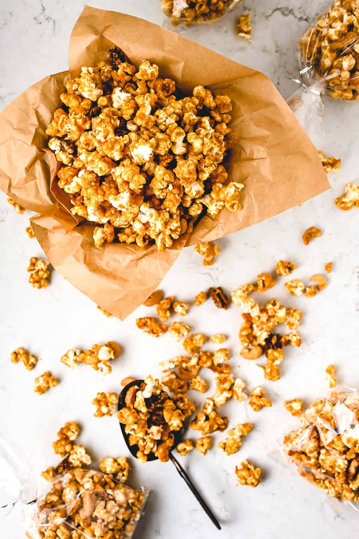 Pumpkin Spice Caramel Popcorn in a parchment paper lined container with popcorn around it.