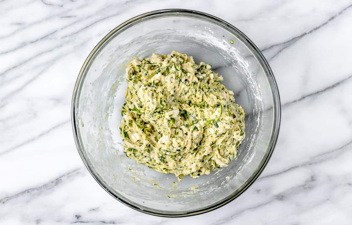 Zucchini fritter dough in a glass bowl.