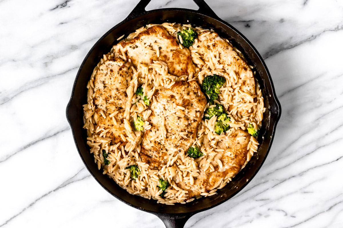 Cooked orzo, chicken and broccoli in a cast iron skillet.