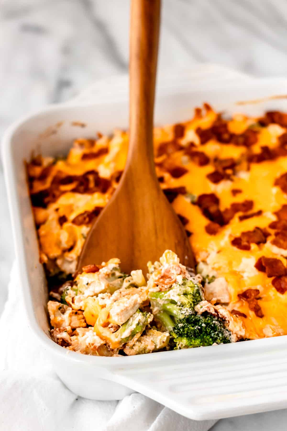 A wood serving lifting up a serving of Bacon Ranch Chicken Casserole.
