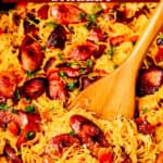 Sausage and spaghetti squash skillet with a wood turner and text overlay.