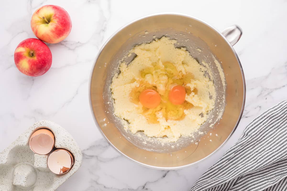Butter and sugar beat together in a mixing bowl with eggs on top.