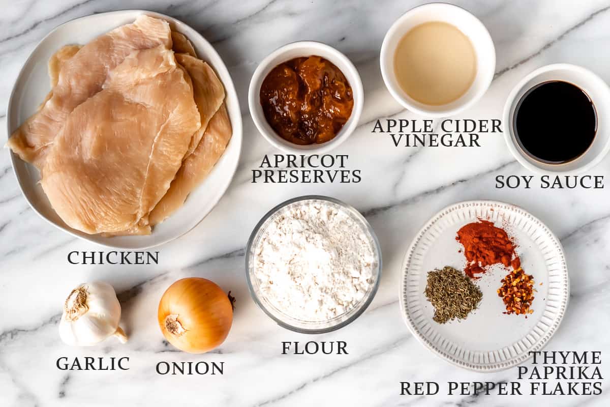 Ingredients to make apricot chicken on a marble background with text overlay.