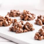 Close up of several chocolate peanut clusters on a white tray.