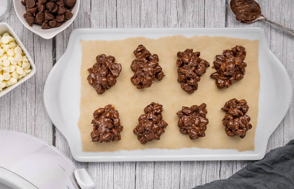 Peanut clusters with salt sprinkled into them on a parchment paper lined tray.