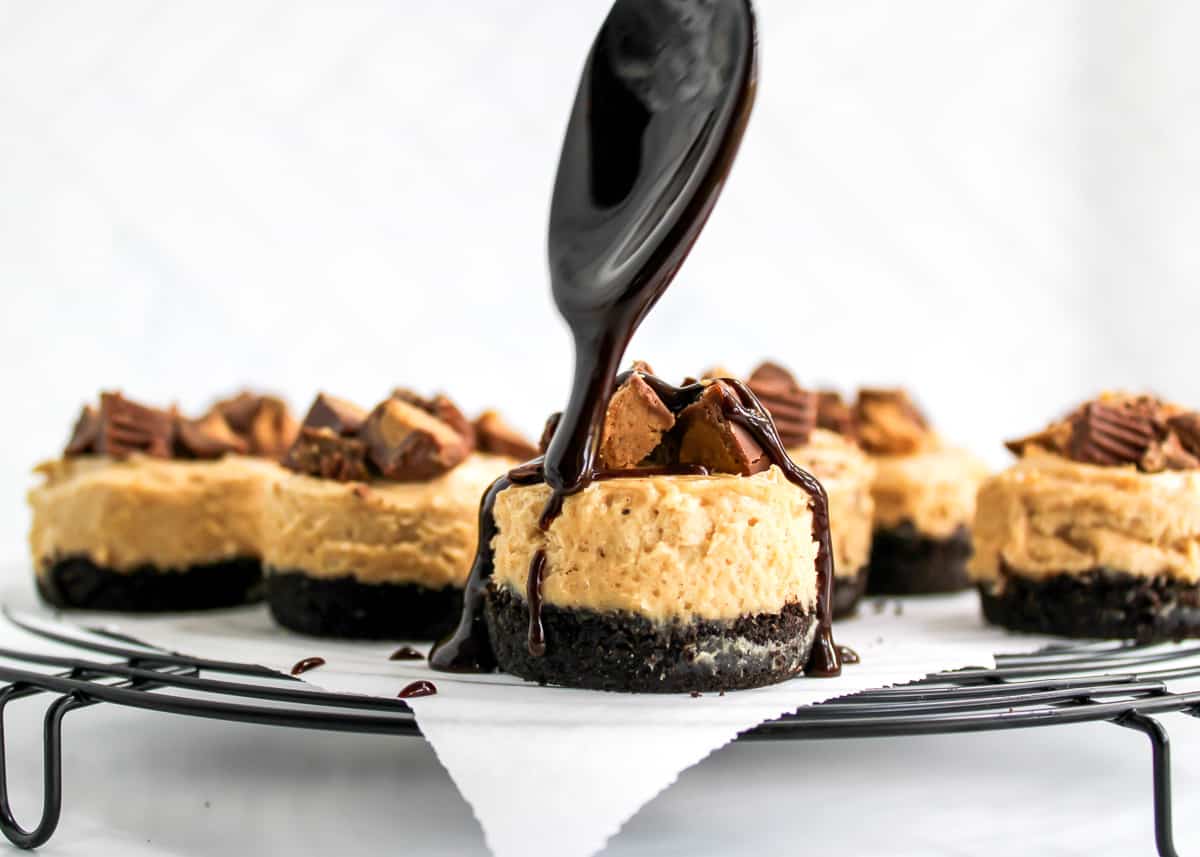 Melted chocolate being drizzled over mini peanut butter pies.