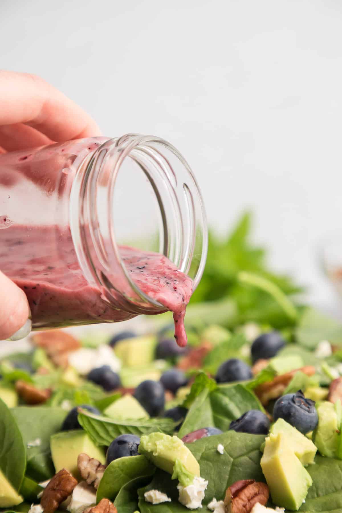 Blueberry salad dressing being poured over a salad.