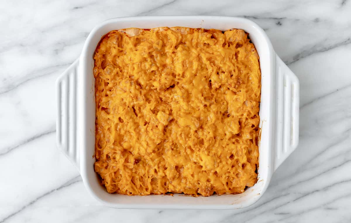 A baked buffalo chicken spaghetti squash casserole in a white, square casserole dish.