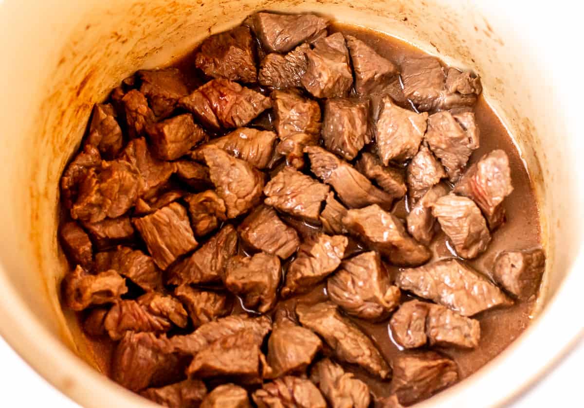 Cubes of cooked steak in the bottom of a stock pot.