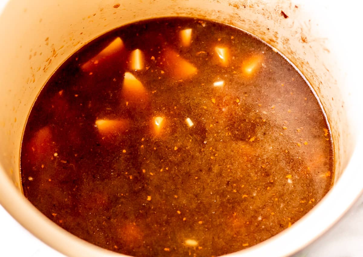 Beef stock and potatoes cooking in a stock pot.