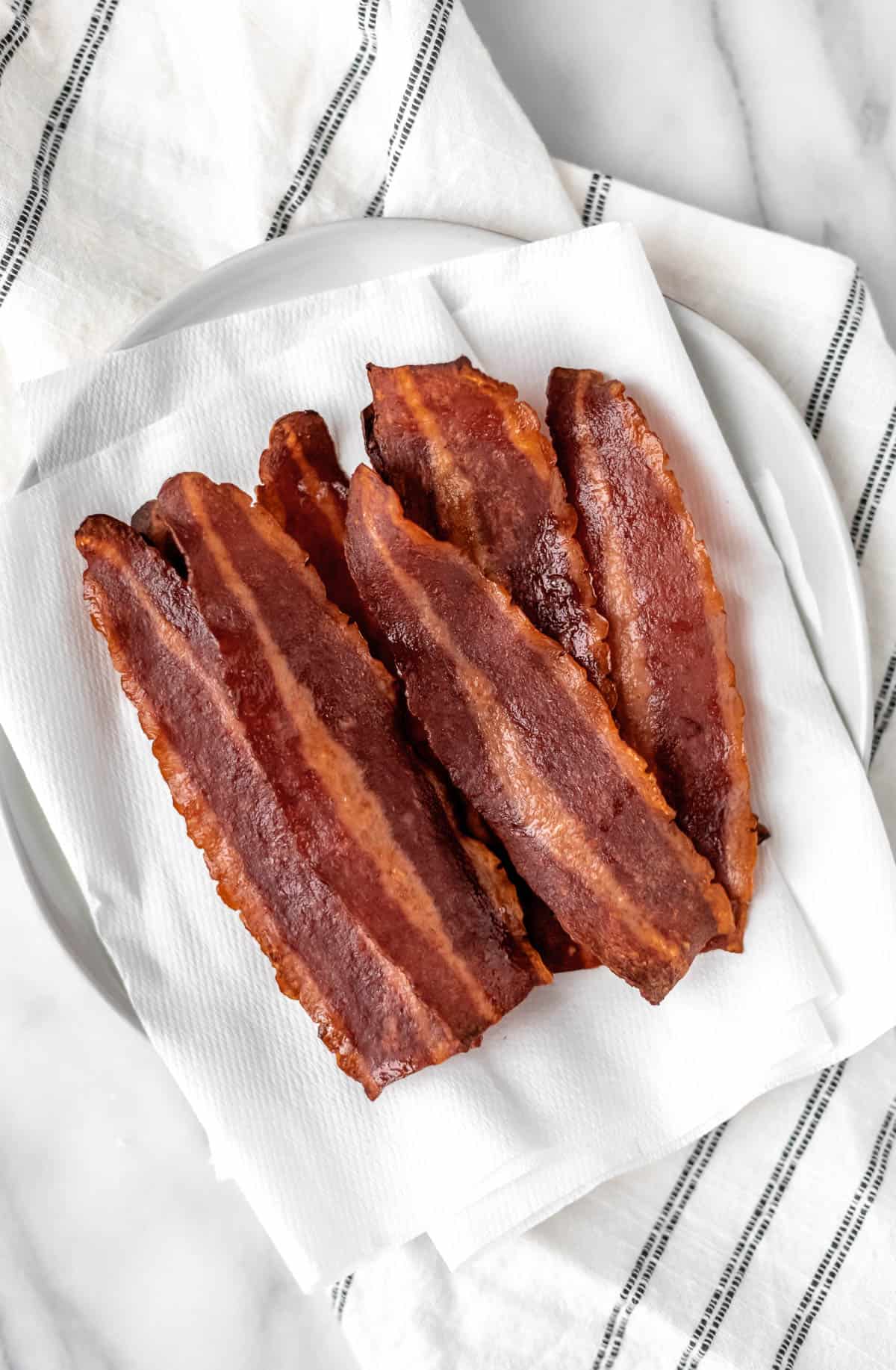 Cooked turkey bacon piled on a paper towel lined plate.