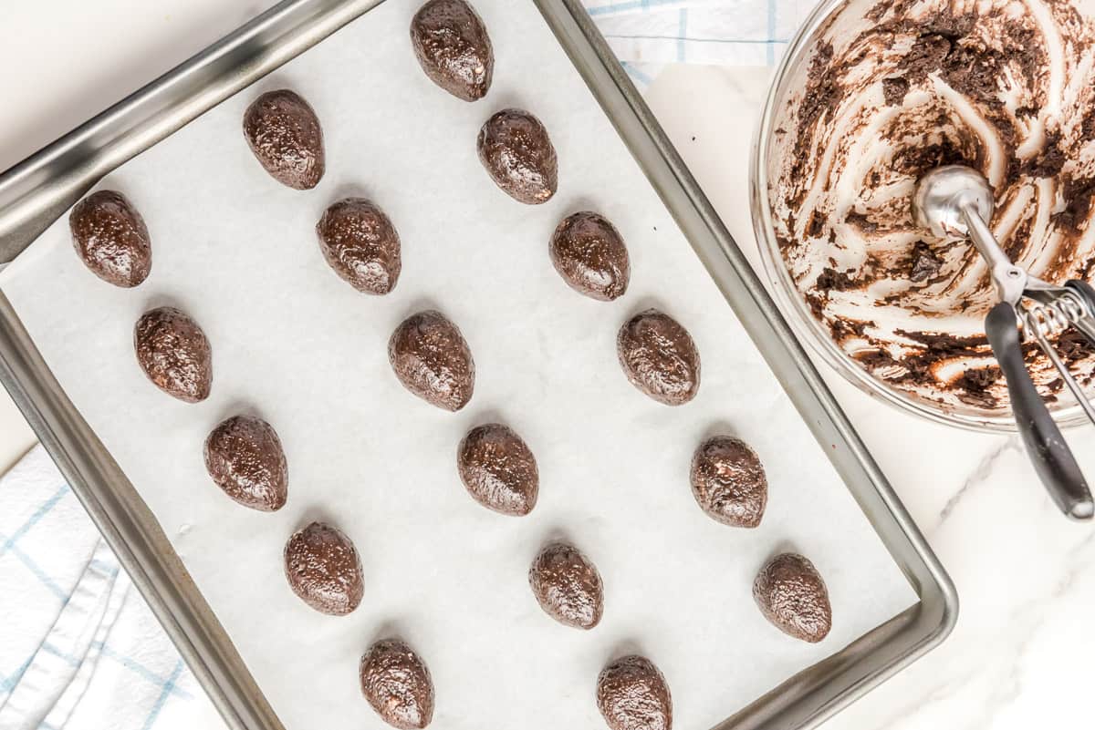 Easter egg shaped Oreo truffles on a parchment paper lined baking sheet.