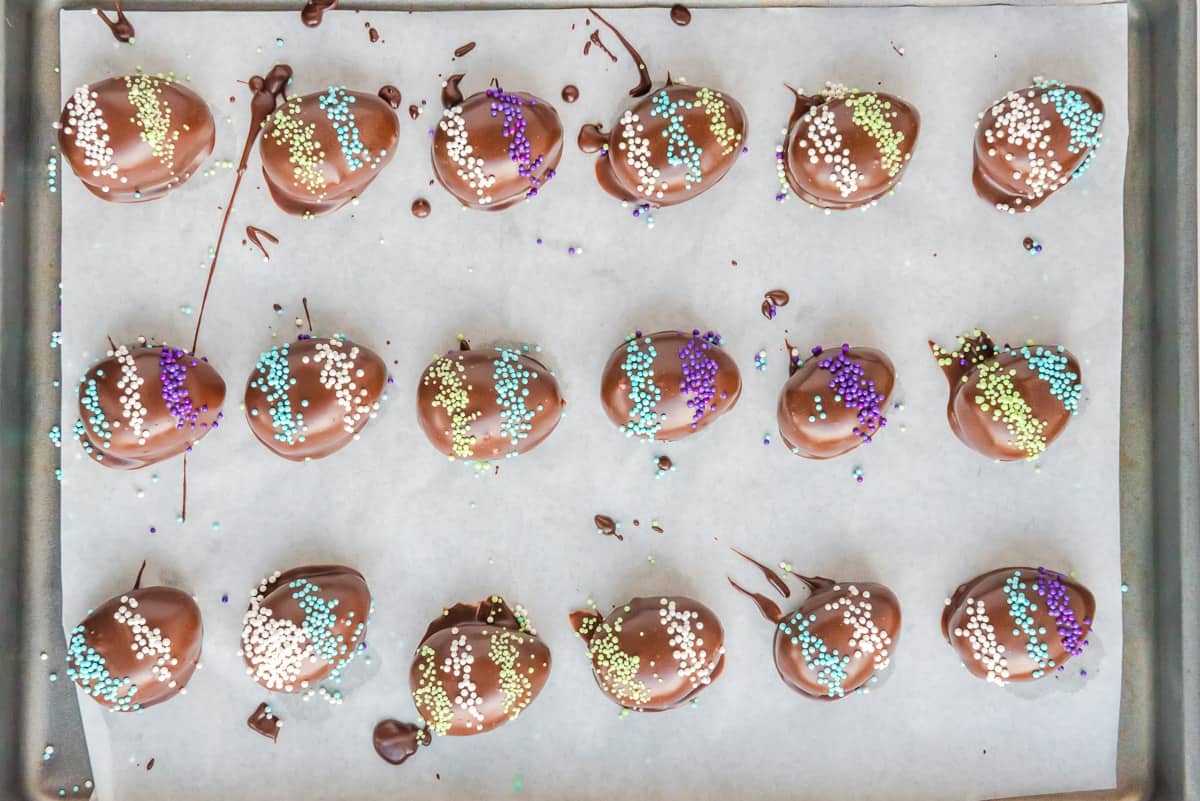 Decorated Easter Egg truffles on a parchment paper lined baking sheet.