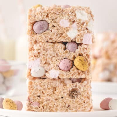 Three Easter Rice Krispies Treats stacked on top of each other with some mini candy eggs around them.