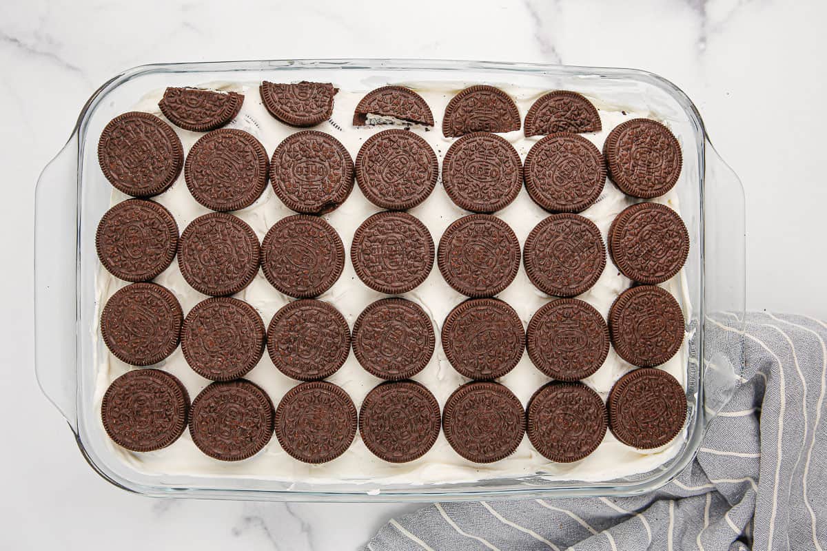 Cream cheese mixture topped with Oreo cookies in a 9x13-inch baking dish.