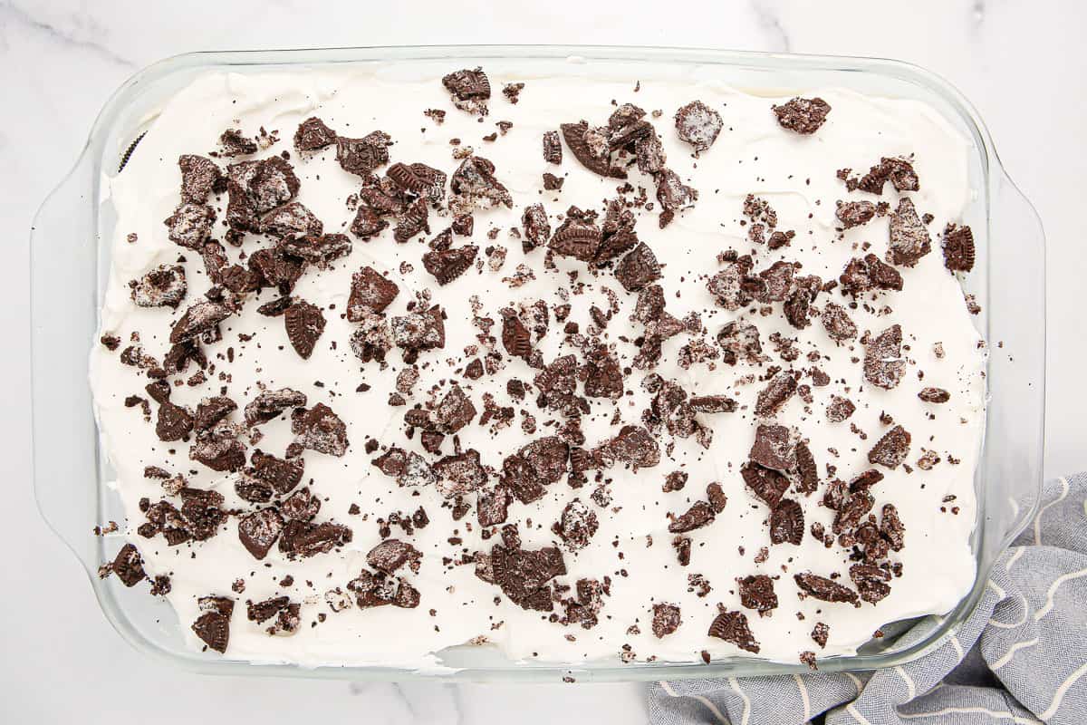Overhead of an Oreo Icebox Cake topped with crushed Oreo cookies in a 9x13-inch baking dish.