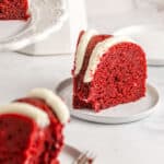 A slice of red velvet pound cake on a white plate with a second slice in the foreground and text overlay.
