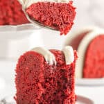 A close up of a slice of red velvet pound cake with a bite taken out of it and more cake in the background with text overlay.