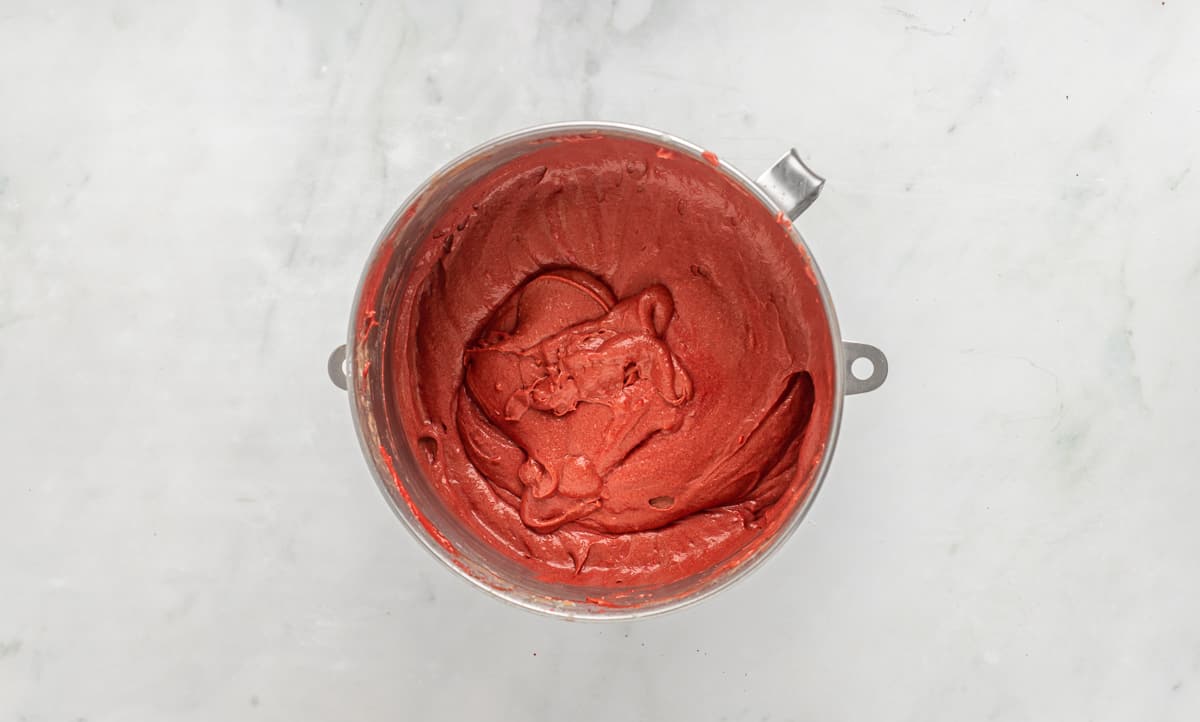 Red velvet cake batter in a silver mixing bowl.
