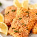 Air fryer cod on a plate with lemons with text overlay.