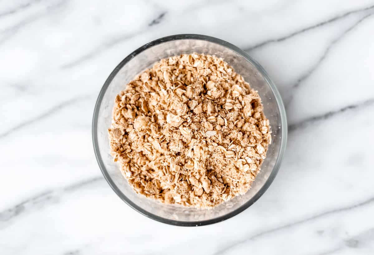 Oat crisp mixture in a gladd bowl over a marble background.