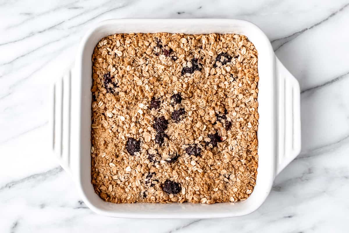 A baked blackberry crisp in a white, square baking dish.