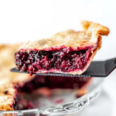 A slice of blackberry pie being lifted up.